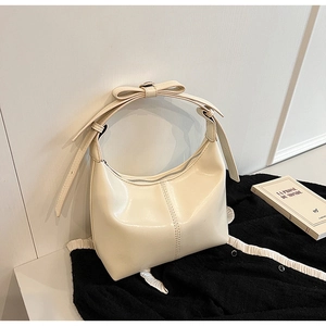Close-up of off-white hobo bag with a decorative bow on the strap and glossy finish