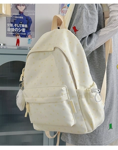 Detail of a creamy white canvas backpack with yellow star patterns and plush charm
