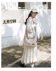 Outdoor shot of a beige water-resistant nylon crescent messenger bag with zipper detail