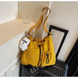 Detail of yellow nylon drawstring bag with plush charm on striped luggage