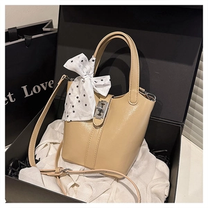 Dettaglio della borsa a secchiello beige con fibbia in argento lucido e foulard di seta