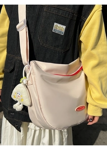 Beige nylon dumpling bag with red zipper and cute mushroom pendant shown in street style