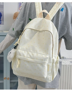 Detail view of cream star-patterned backpack with a white plush cloud accessory
