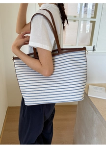 Detail of blue and white striped canvas tote with brown leather strap and gold ring
