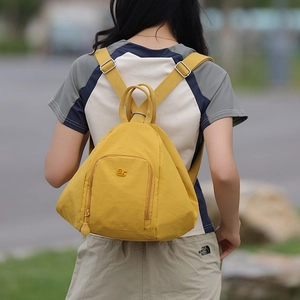 Outdoor view of a bright yellow nylon triangular backpack with adjustable straps and logo