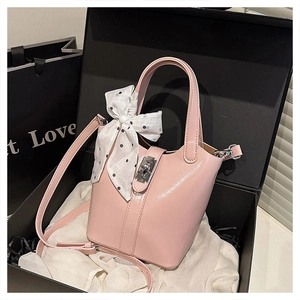 Dettaglio borsa a secchiello rosa con fiocco di seta a pois e chiusura metallica