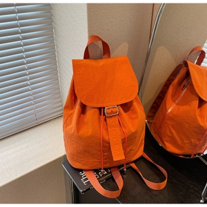 Détail d'un sac à dos en nylon orange vif avec cordon de serrage et boucle métallique
