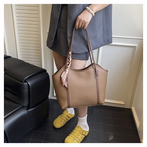 Close-up of brown litchi pattern leather tote bag with silk scarf on handle