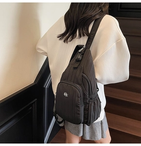 Detail of black sporty crossbody bag with unique pleated texture and adjustable buckle strap