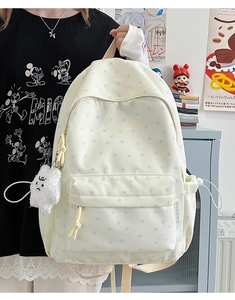 Macro shot of a cream canvas backpack with blue star prints and plush cloud charm