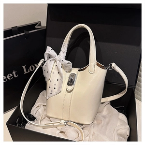 Dettaglio borsa a secchiello bianco crema con chiusura argento e foulard in scatola regalo