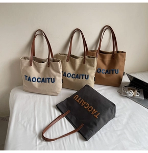 Detail showing variety of canvas tote bags with leather straps and logo embroidery