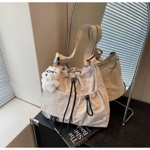 Close-up of beige nylon bucket bag with black drawstrings and plush dog charm