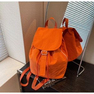 Détail d'un sac à dos orange en nylon imperméable avec boucle en métal et cordon de serrage