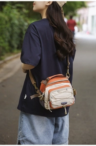 Outdoor detail of a versatile orange and white nylon crossbody bag with elastic cord