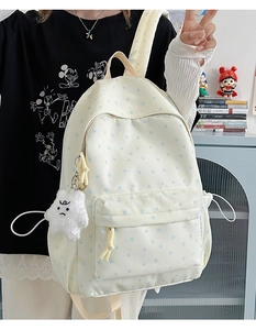 Detail of cream canvas backpack featuring blue star patterns and star plush pendant