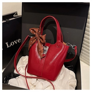 Dettaglio borsa a secchiello in pelle rossa con chiusura argento e foulard in seta a pois