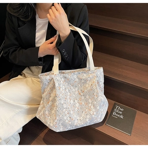 Detail of floral lace canvas tote bag with woven handles shown in a lifestyle setting