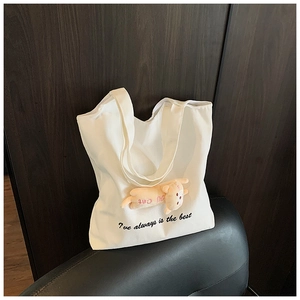 Detailed view of the thick white canvas tote bag with a 3D plush orange cat pendant