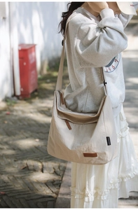 Detail of water-resistant cream nylon messenger bag with adjustable strap and logo tag