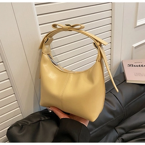 Détail du sac demi-lune en cuir jaune crème avec des nœuds élégants sur la bandoulière