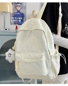 Detail of cream canvas backpack featuring blue star patterns and a plush cloud charm