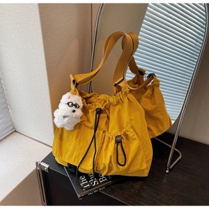 Detailed close-up of a large yellow nylon bucket bag with drawstring and cute puppy charm