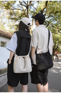 Outdoor view of couple wearing large nylon drawstring bucket bags in cream and black