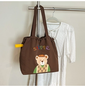 Detail of cute bear embroidery and Steppe text on brown canvas tote bag with drawstring