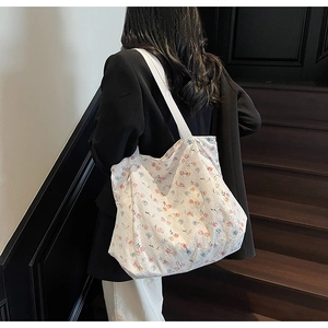 Detail of floral canvas tote bag with soft cotton texture shown on model's shoulder