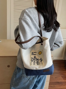 Minimalist canvas tote bag with contrast colors and leather straps on woman's shoulder