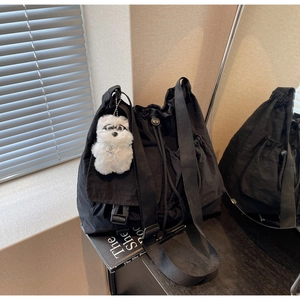 Detail of black drawstring crossbody bag featuring a cute white plush puppy charm