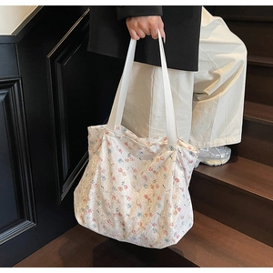 Detail shot of a white floral canvas tote bag with pink and blue flower patterns on stairs