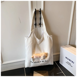 Close-up of white canvas tote bag featuring a 3D plush cat doll and embroidered text detail