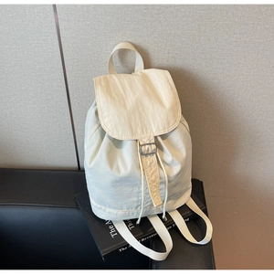 Détail du sac à dos en nylon crème avec fermeture à rabat sur un canapé moderne