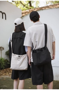 Outdoor shot showing back view of nylon drawstring bucket bag with wide shoulder strap