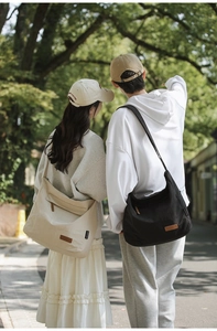 Outdoor shot showing a large beige nylon messenger bag with a durable crossbody strap