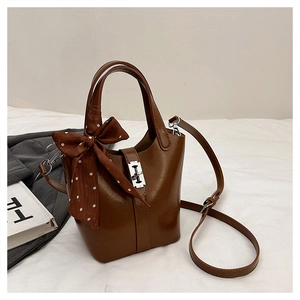 Dettaglio della borsa a secchiello in pelle marrone con foulard e chiusura in metallo