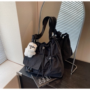 Detail of black large capacity nylon drawstring bag with a cute plush dog pendant