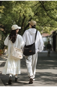 Lighweight waterproof oxford crossbody bag shown in black and beige on couple models