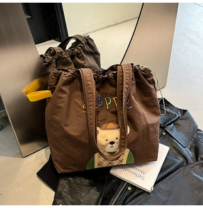 Detailed view of brown canvas tote with cute bear embroidery and drawstring closure