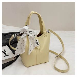 Dettaglio borsa a secchiello in pelle gialla con chiusura argento e foulard a pois