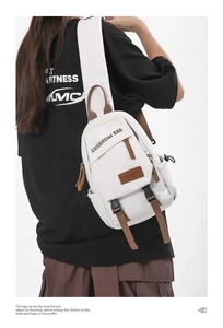 Detail of white nylon chest bag featuring brown leather trim and zip pockets