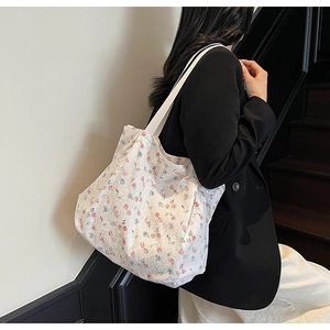 Detail of floral canvas tote bag with lace overlay shown on model in modern setting