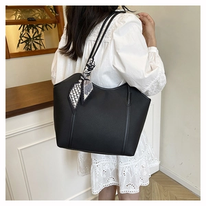 Black tote bag detail with geometric scarf on handle shown on shoulder in daily life