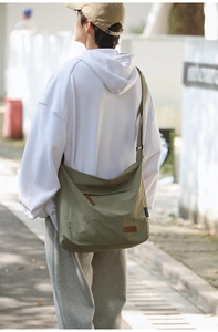 Rear view of olive green oversized canvas crossbody bag worn with a white hoodie