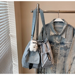 Detail of light blue nylon drawstring bucket bag with adjustable strap and plush puppy charm