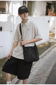 Outdoor lifestyle shot of a large beige nylon drawstring shoulder bag in a pleated design