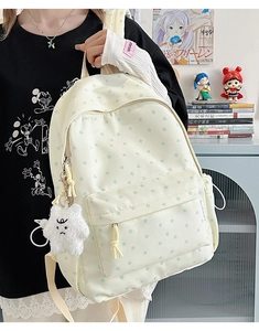 Detail of cream canvas backpack featuring green star prints and fuzzy star keychain