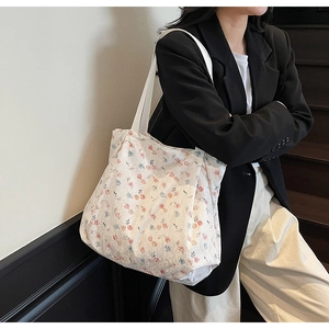 Close-up of white canvas tote bag with pink and blue floral patterns on a shoulder strap
